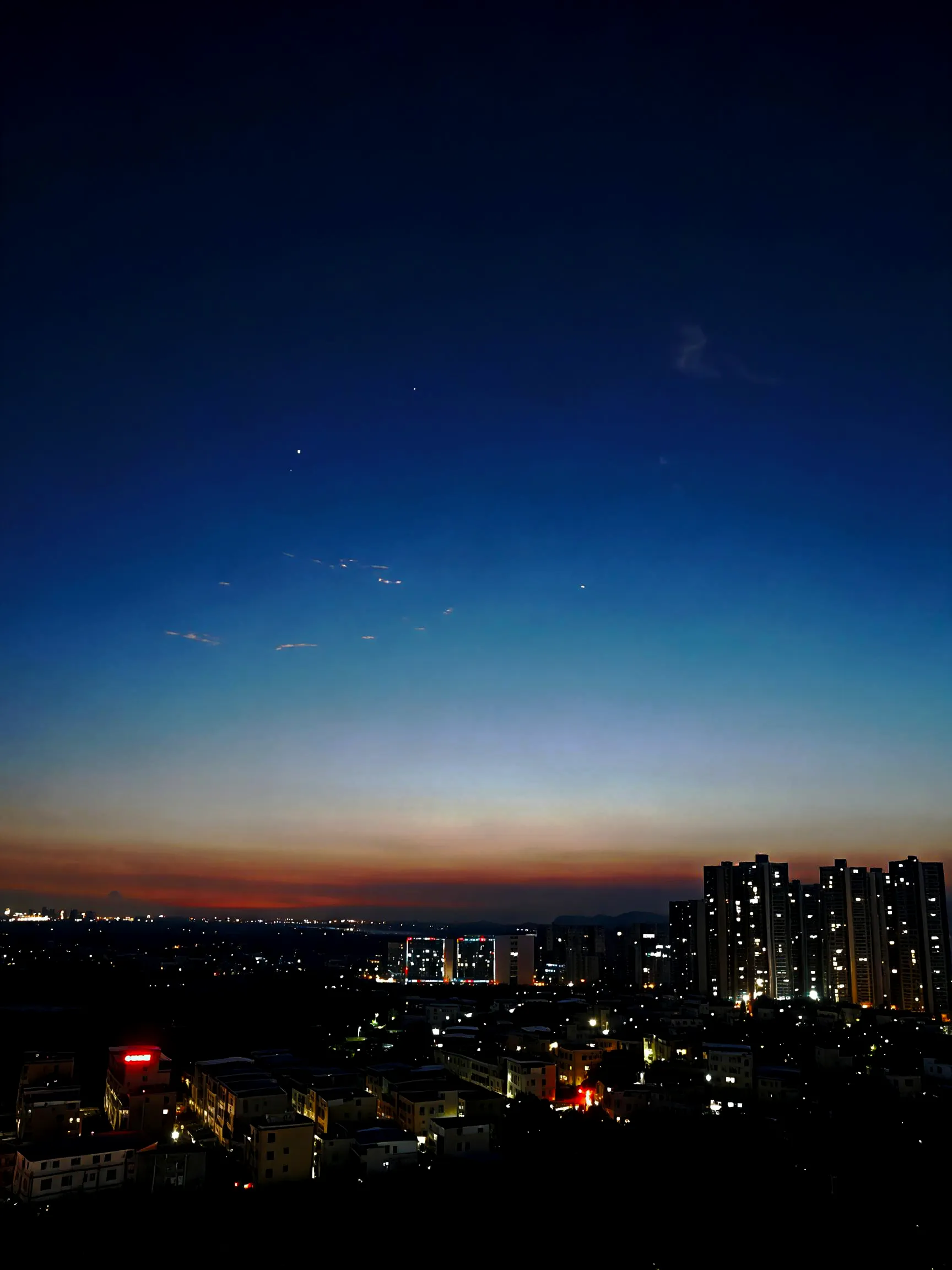 惠州城市夜景，蓝调时刻，天空由深蓝渐变到地平线的橙红余晖，城区灯火密集